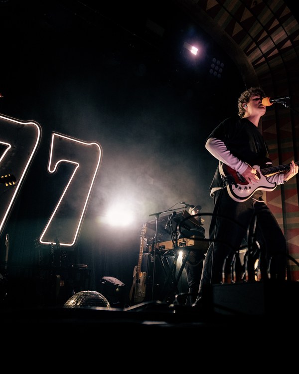 A band playing live beside a giant neon 77